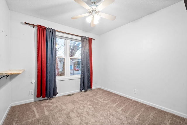 carpeted spare room featuring a textured ceiling and ceiling fan