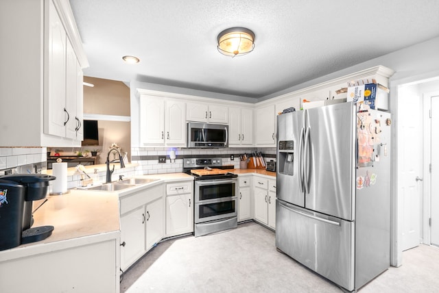 kitchen featuring white cabinets, backsplash, sink, and appliances with stainless steel finishes