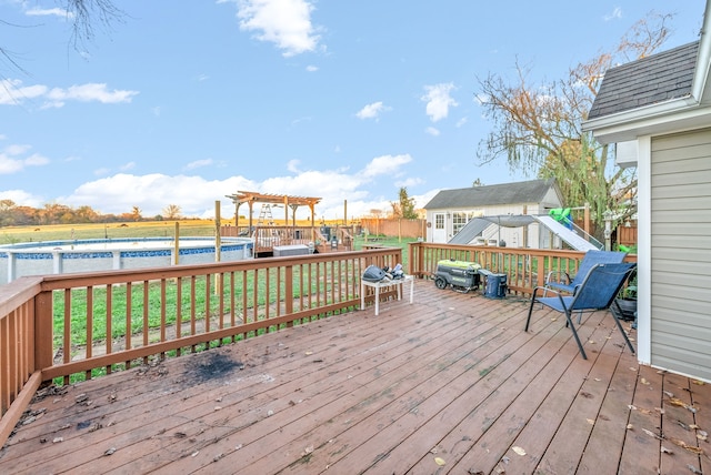 wooden deck featuring a pergola, a fenced in pool, and a lawn