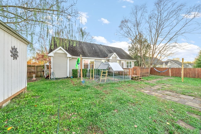 rear view of property featuring a lawn, an outdoor structure, and a wooden deck