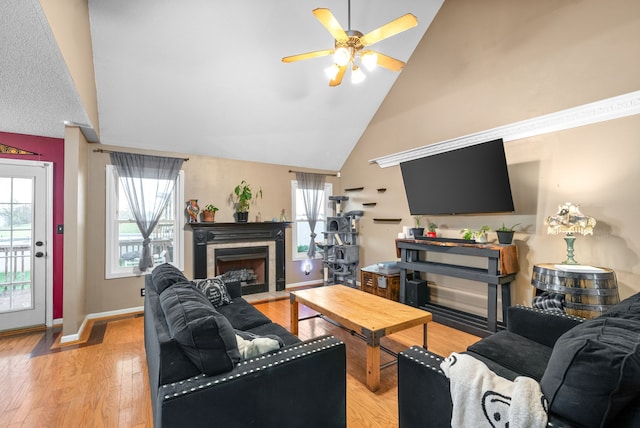 living room with ceiling fan, high vaulted ceiling, and light wood-type flooring