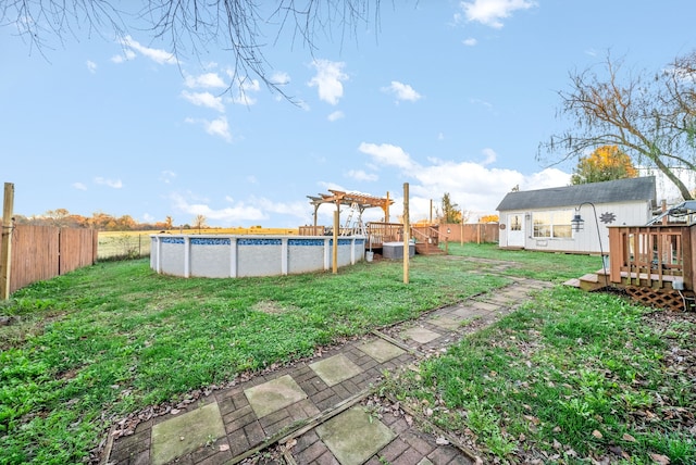 view of yard featuring an outbuilding, a swimming pool side deck, and a pergola