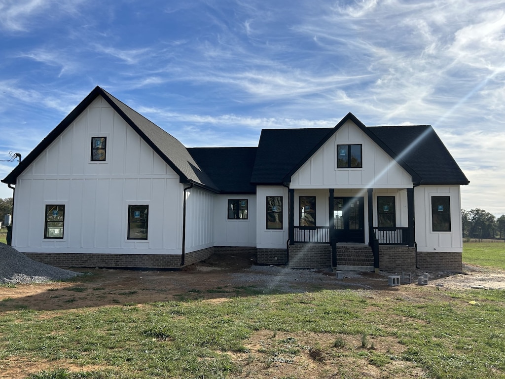 modern inspired farmhouse featuring covered porch and a front yard