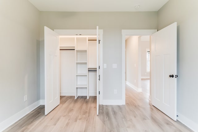 unfurnished bedroom with light wood-type flooring and a closet