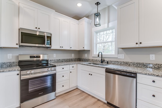 kitchen with light stone countertops, white cabinetry, sink, light hardwood / wood-style flooring, and appliances with stainless steel finishes