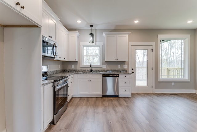 kitchen featuring a wealth of natural light, pendant lighting, stainless steel appliances, and sink