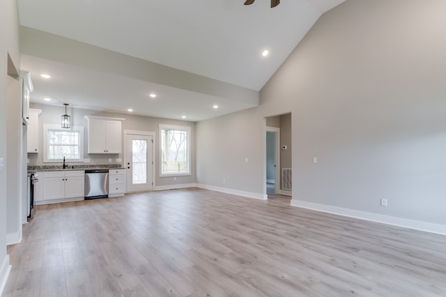 unfurnished living room with ceiling fan, light hardwood / wood-style floors, sink, and high vaulted ceiling