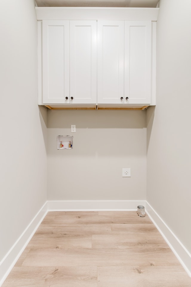 laundry area with light hardwood / wood-style floors, cabinets, and hookup for a washing machine