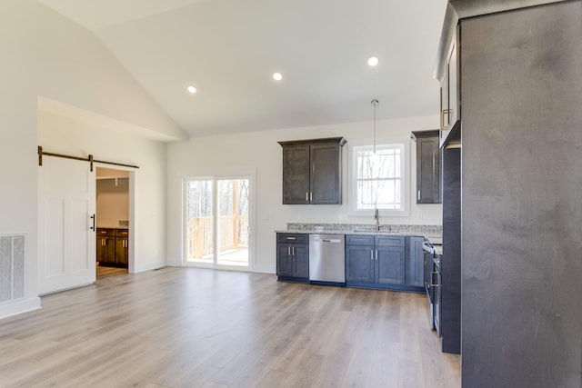 kitchen with pendant lighting, sink, vaulted ceiling, stainless steel dishwasher, and a barn door