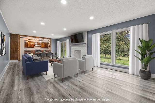 living room featuring a fireplace, a textured ceiling, and light wood-type flooring