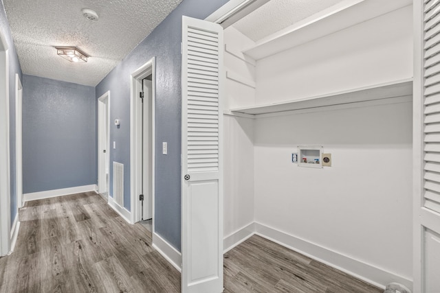 clothes washing area featuring washer hookup, electric dryer hookup, a textured ceiling, and hardwood / wood-style flooring