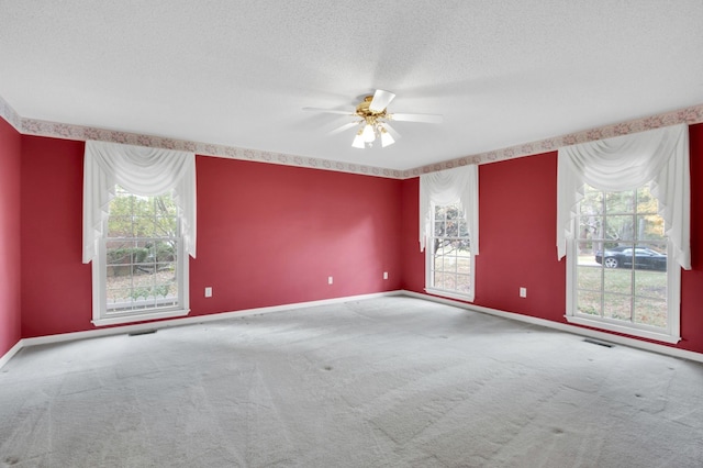 carpeted empty room featuring a textured ceiling, a healthy amount of sunlight, and ceiling fan