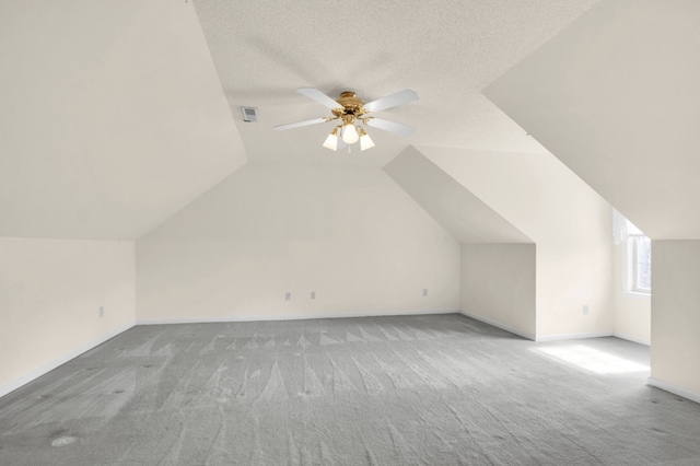 bonus room with lofted ceiling, a textured ceiling, light carpet, and ceiling fan