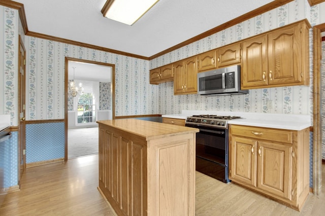 kitchen featuring black gas range oven, light wood-type flooring, an inviting chandelier, and ornamental molding