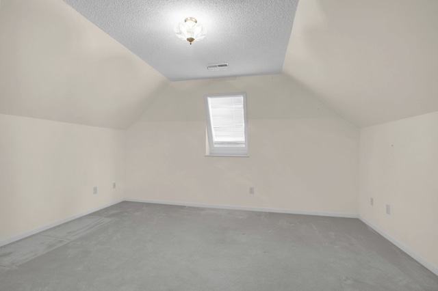 bonus room with lofted ceiling with skylight, a textured ceiling, and light colored carpet