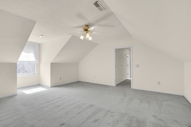 additional living space featuring a textured ceiling, light colored carpet, lofted ceiling, and ceiling fan