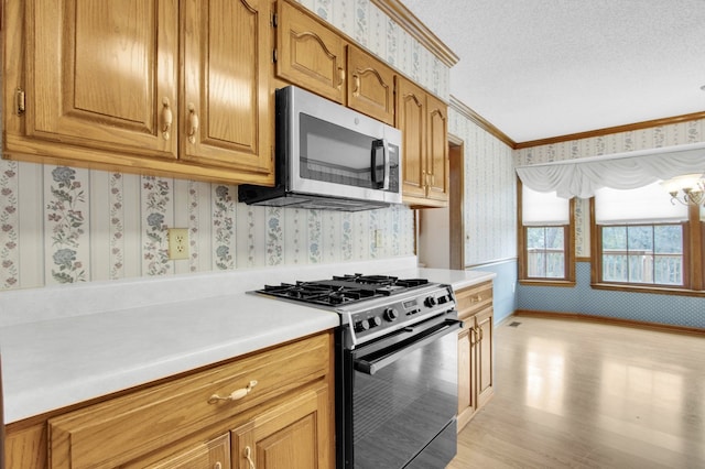 kitchen with appliances with stainless steel finishes, a textured ceiling, crown molding, and light hardwood / wood-style flooring