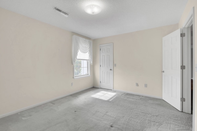 empty room with a textured ceiling and light carpet