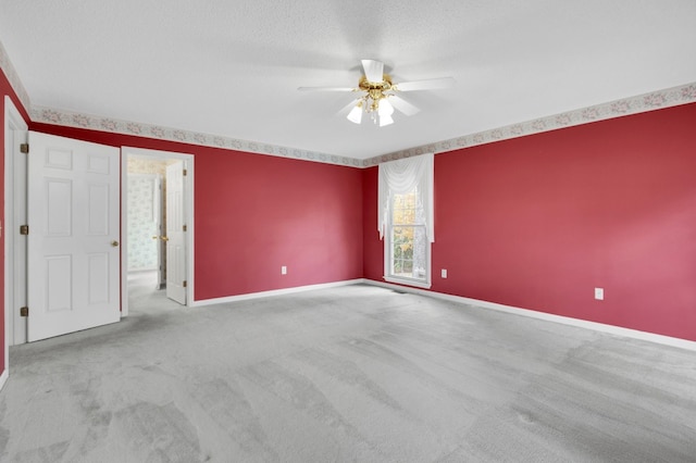 empty room featuring ceiling fan, a textured ceiling, and light colored carpet