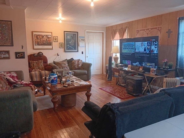 living room featuring wood walls, hardwood / wood-style flooring, radiator heating unit, and crown molding