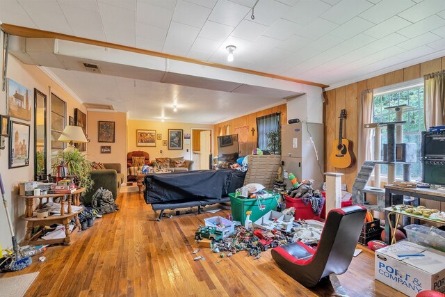 living room featuring wood walls, hardwood / wood-style flooring, and ornamental molding