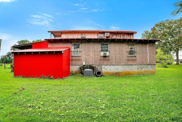 rear view of property with central AC unit, a lawn, and cooling unit