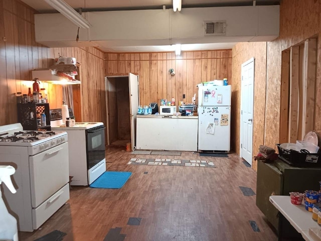 kitchen with dark wood-type flooring, white appliances, and wooden walls