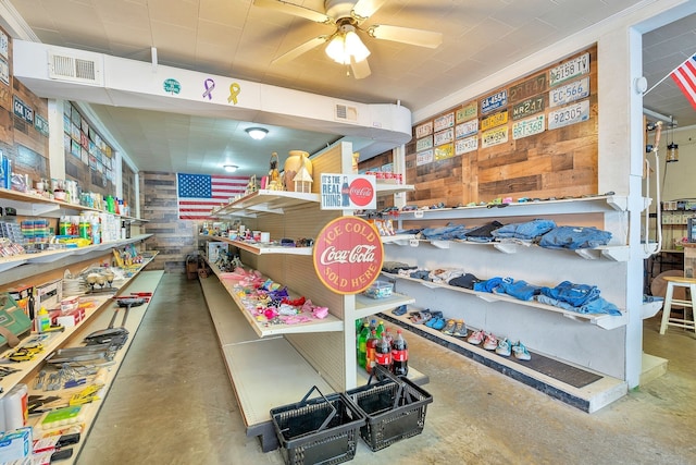 interior space featuring wooden walls, concrete floors, and ceiling fan