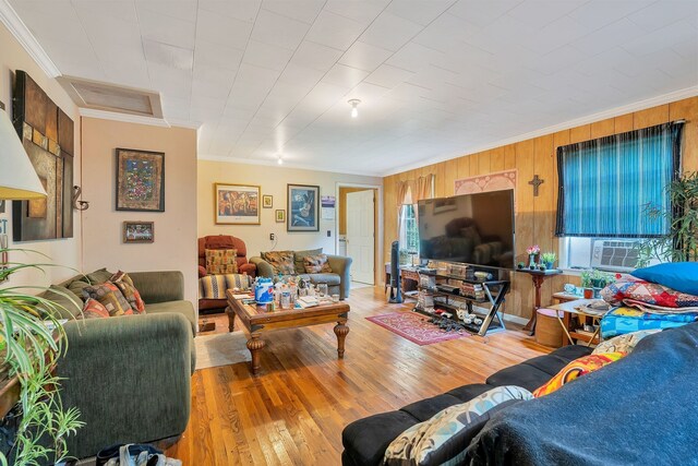 living room featuring hardwood / wood-style flooring, wooden walls, and ornamental molding