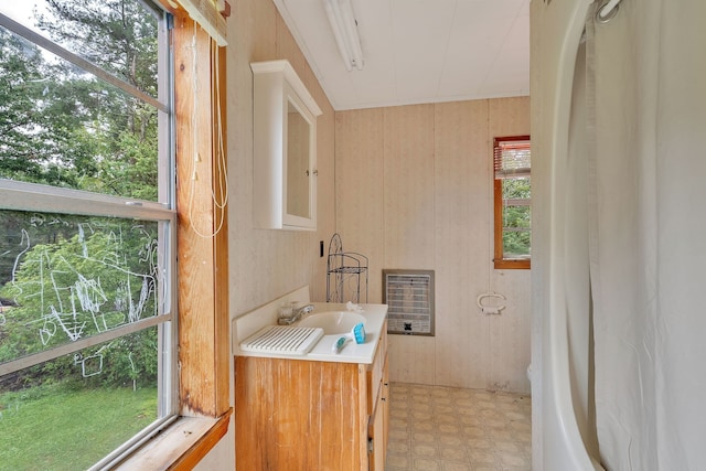 bathroom with a wealth of natural light, wooden walls, sink, and heating unit