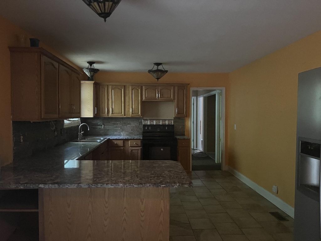 kitchen with tile patterned floors, kitchen peninsula, decorative backsplash, sink, and black range with electric cooktop