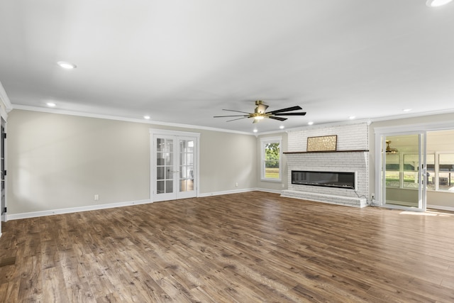 unfurnished living room with hardwood / wood-style floors, ceiling fan, crown molding, and a brick fireplace