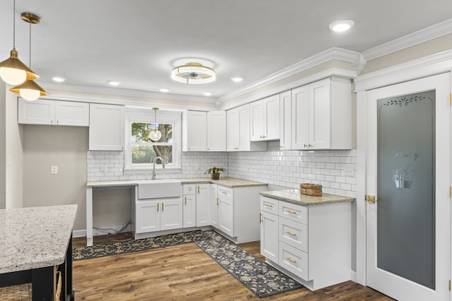 kitchen featuring sink, hanging light fixtures, crown molding, white cabinets, and dark hardwood / wood-style flooring