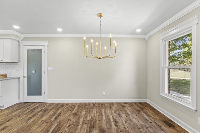 unfurnished dining area featuring dark hardwood / wood-style floors, an inviting chandelier, and ornamental molding