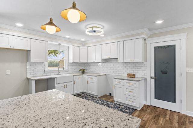 kitchen with dark wood-type flooring, hanging light fixtures, and white cabinets