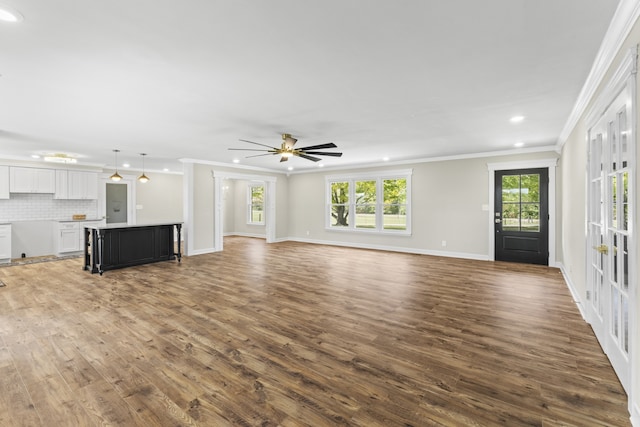 unfurnished living room featuring ceiling fan, dark hardwood / wood-style floors, and ornamental molding