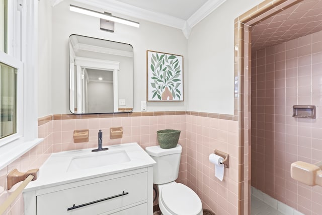 bathroom featuring toilet, tile walls, a tile shower, vanity, and crown molding