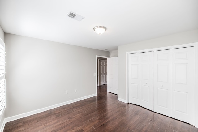 unfurnished bedroom with dark hardwood / wood-style floors and a closet