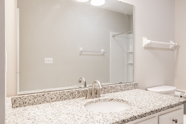 bathroom with walk in shower, vanity, and toilet