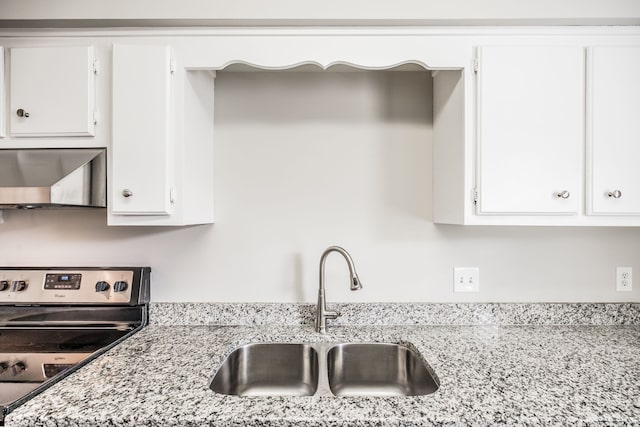 kitchen featuring stainless steel electric stove, sink, wall chimney exhaust hood, light stone countertops, and white cabinetry