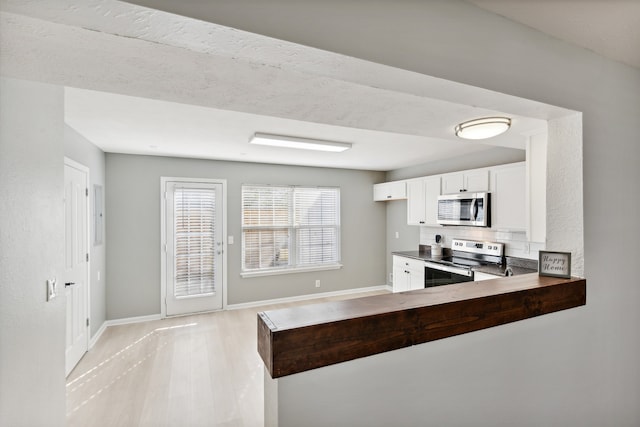 kitchen featuring white cabinetry, kitchen peninsula, stainless steel appliances, and light hardwood / wood-style floors