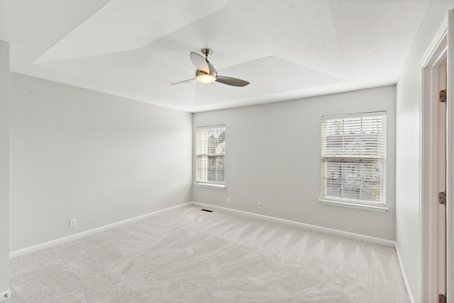 empty room featuring a wealth of natural light, ceiling fan, and light colored carpet