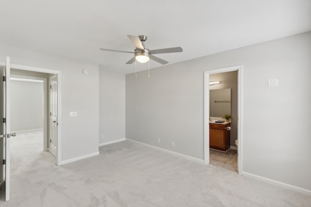 unfurnished bedroom featuring ensuite bath, ceiling fan, and light colored carpet