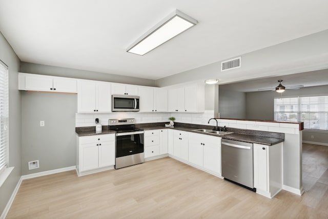 kitchen featuring stainless steel appliances, sink, tasteful backsplash, white cabinetry, and light hardwood / wood-style flooring