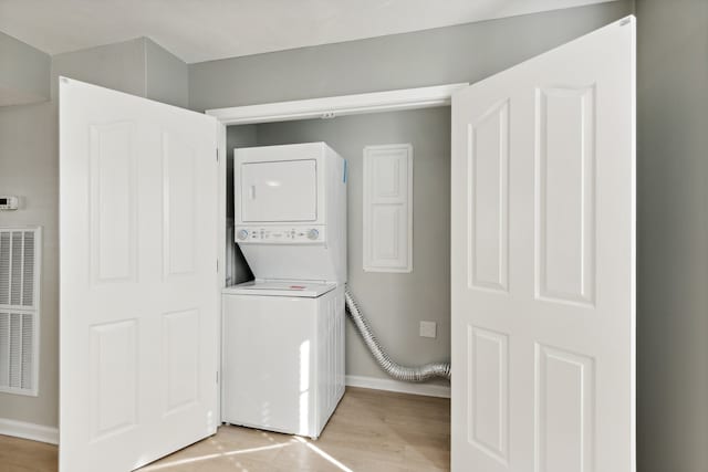 laundry area with stacked washer / dryer and light hardwood / wood-style floors