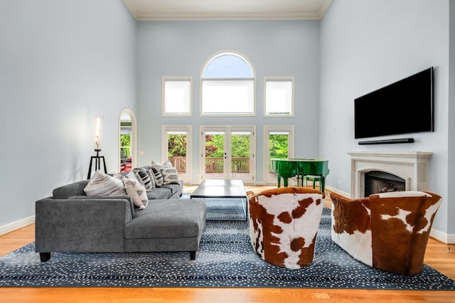 living room with a high ceiling, light wood-type flooring, and ornamental molding