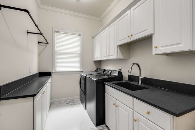 clothes washing area featuring ornamental molding, cabinets, sink, and independent washer and dryer