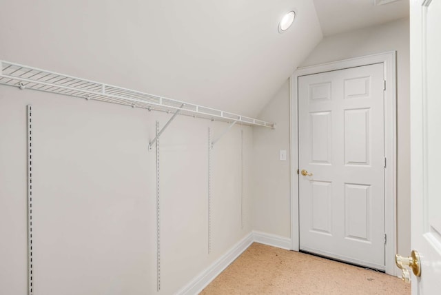 spacious closet with lofted ceiling and light colored carpet