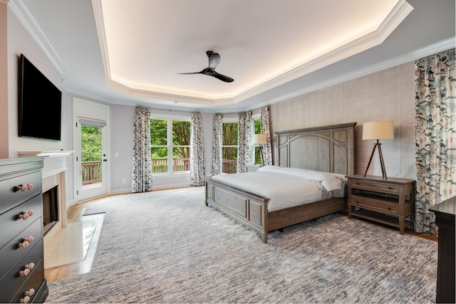 bedroom with ceiling fan, access to exterior, a raised ceiling, and hardwood / wood-style floors