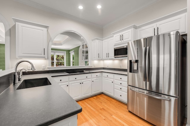 kitchen with stainless steel appliances, sink, crown molding, white cabinetry, and light wood-type flooring